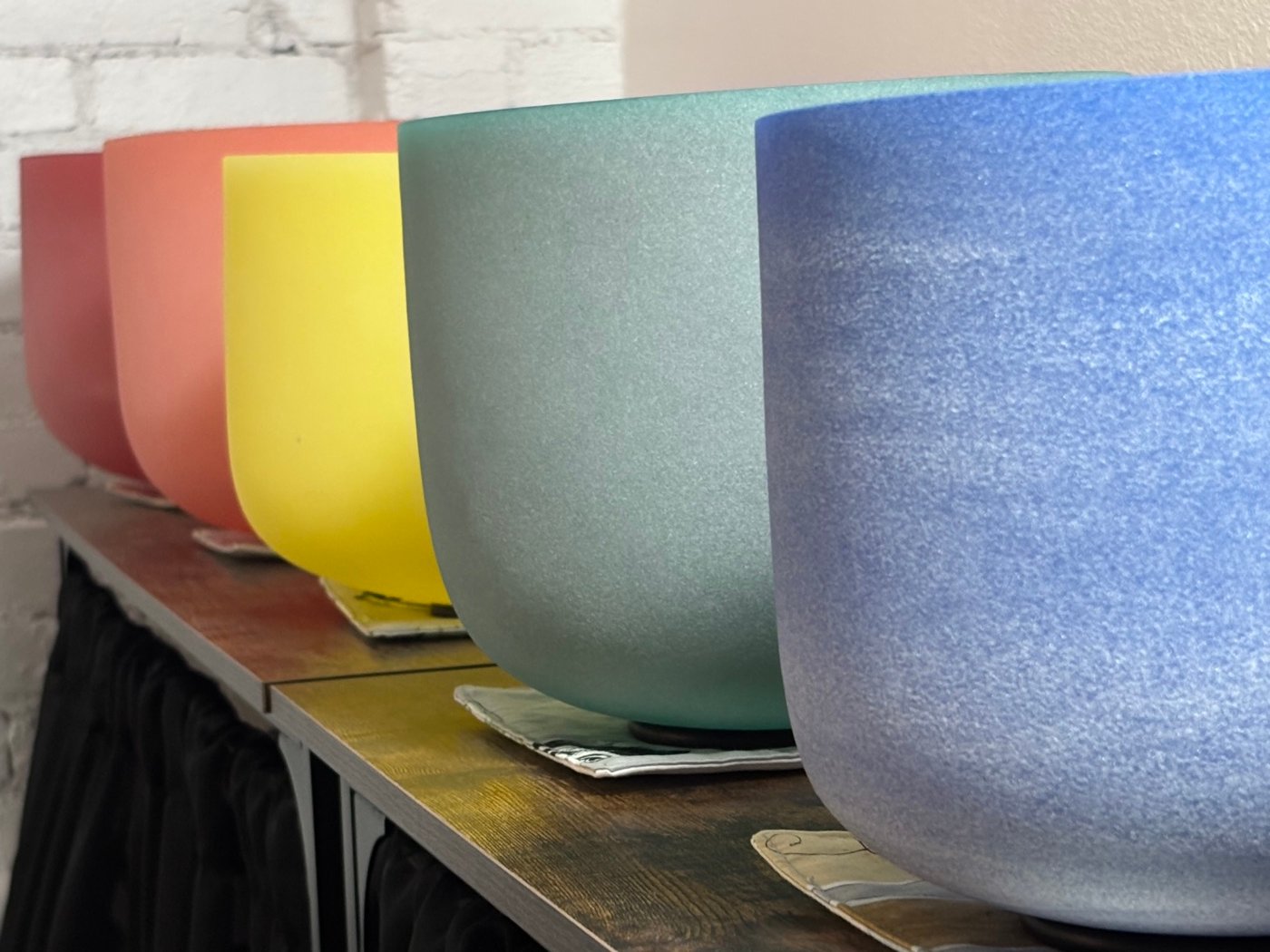 A row of crystal singing bowls in the studio — each one tuned to a different note