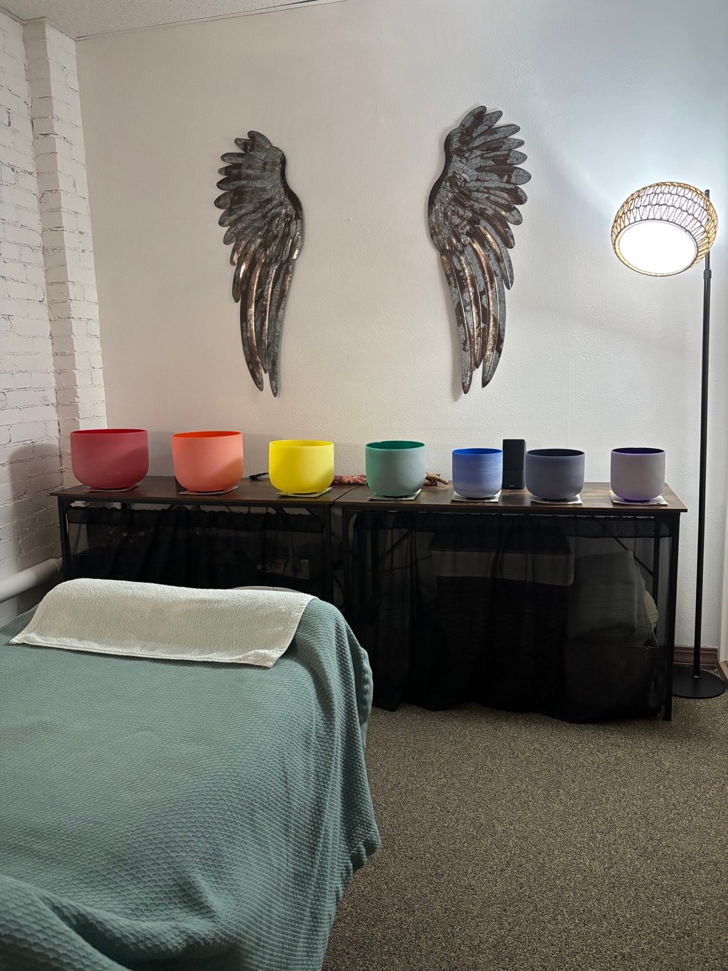 The studio interior — wing wall art beside a rack of crystal singing bowls